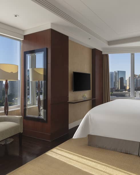 Hotel room with king bed, arm chair and two walls of windows