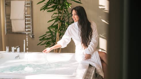Woman sits at side of spa hot tub with spa robe on