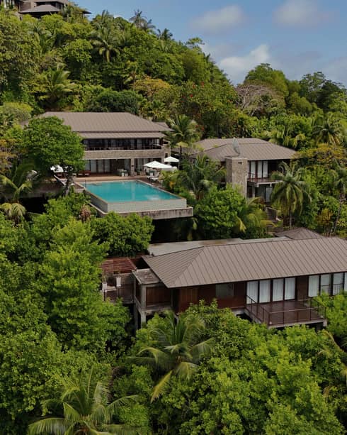 Aerial view of a large private residence with pool nestled on lush ocean-view hillside