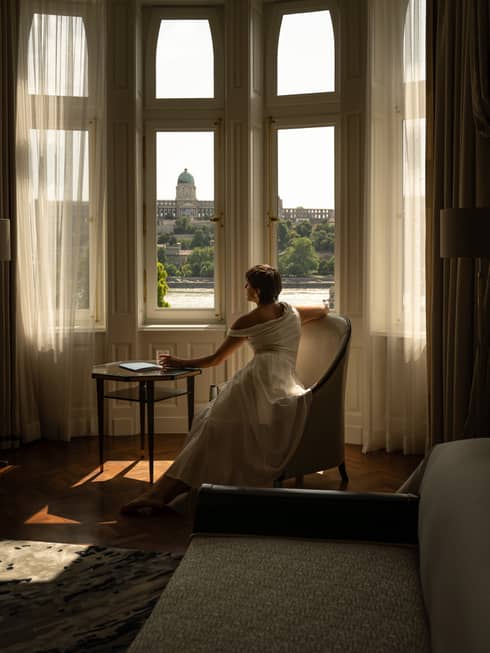 A woman looks out windows of luxury suite