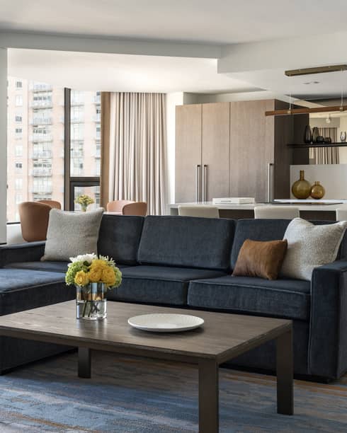 Living room with dark grey sofa, wooden coffee table, kitchen in the back