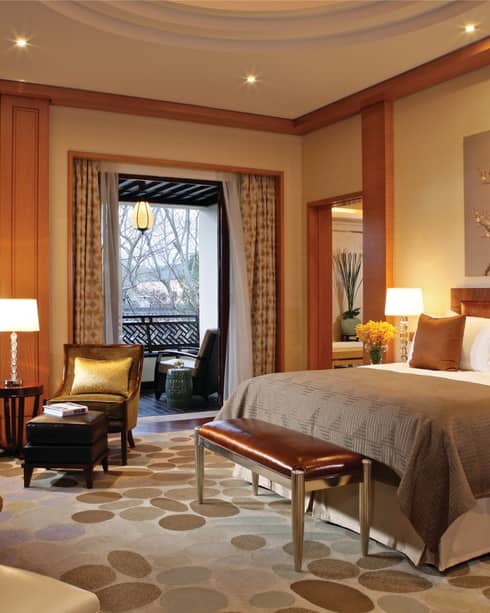 Governor Villa bed with copper pillows, blanket, small leather bench by seating areas, double windows