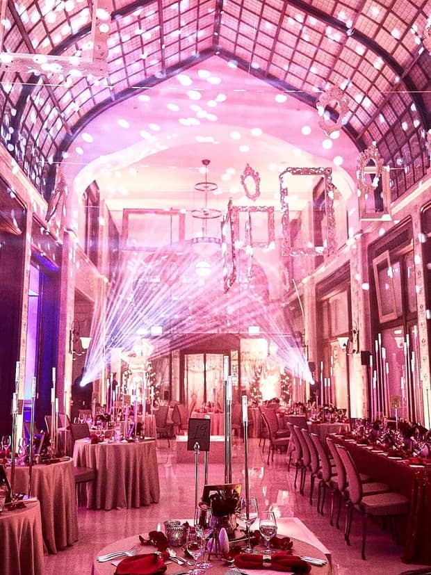 Wedding reception in large event room with arched ceiling and pink lights