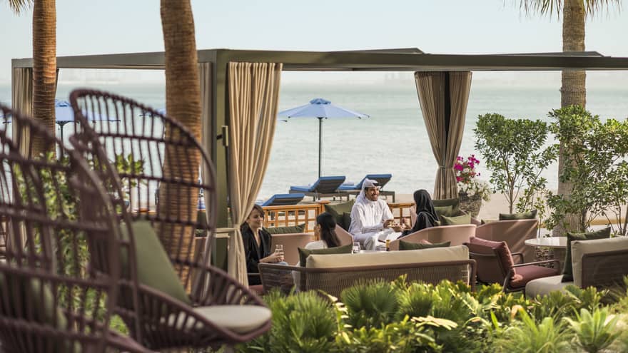 People sitting by the beach in an outdoor seating area in luxury hotel
