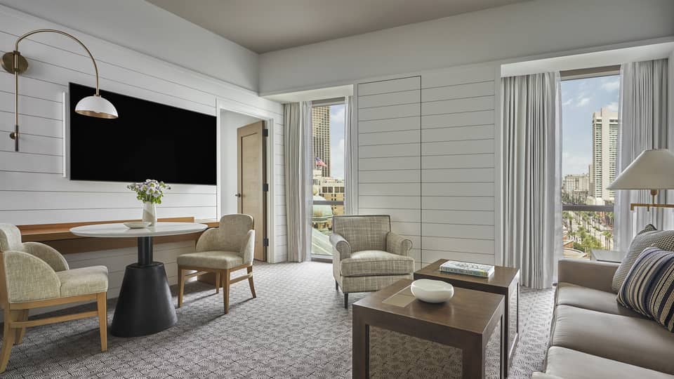 Suite with white panel walls, coffee table, sofa, two chairs, small table and television