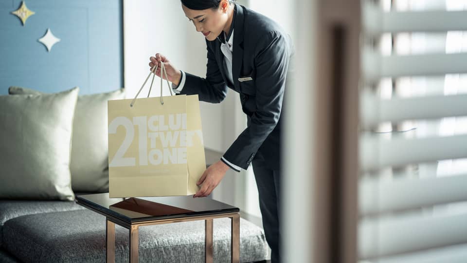 Hotel staff pours coffee from carafe into cup on brunch tray on in-room dining table