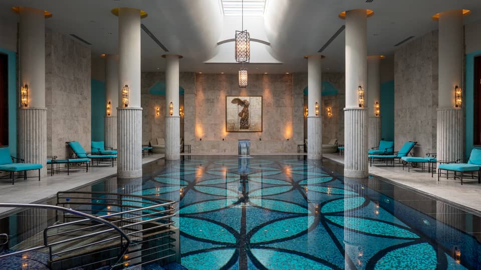 Indoor pool with blue-patterned floor, white up-lit columns and skylight