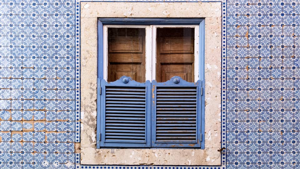 A blue wall and window covered in blue and brown doors.