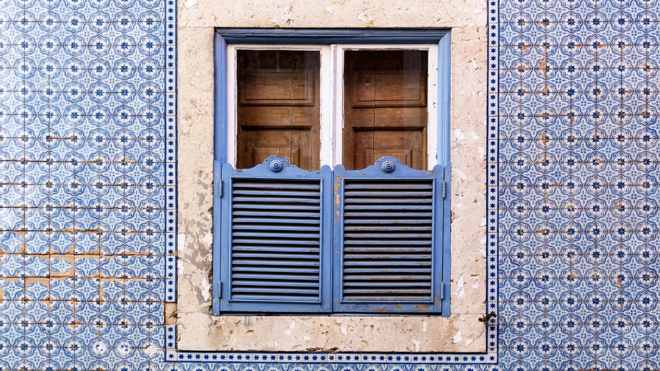 A blue wall and window covered in blue and brown doors.
