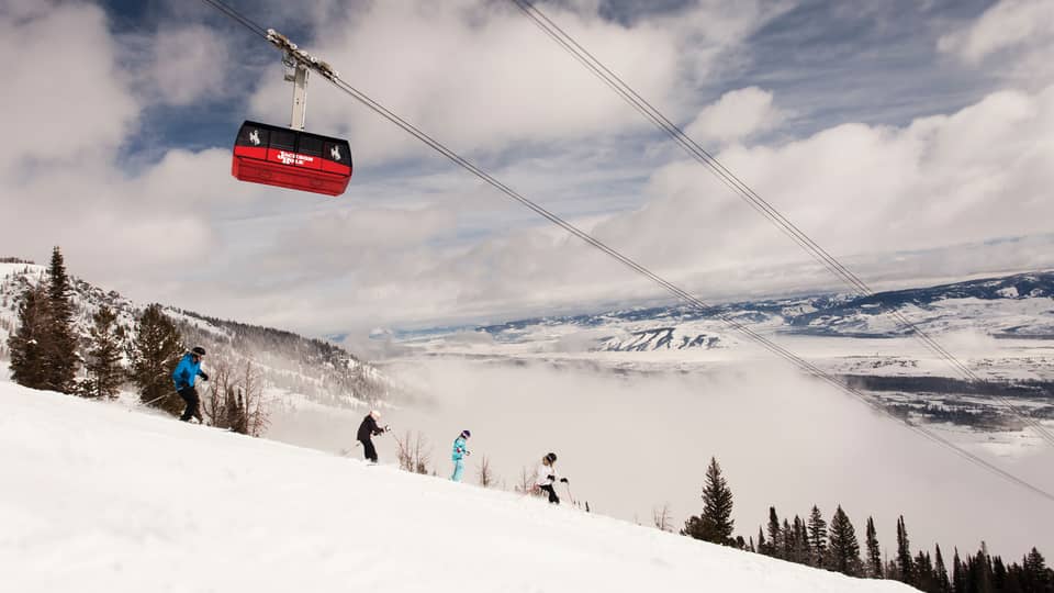 Red Sweetwater Gondola ski lift on wire above hikers on snowy mountain
