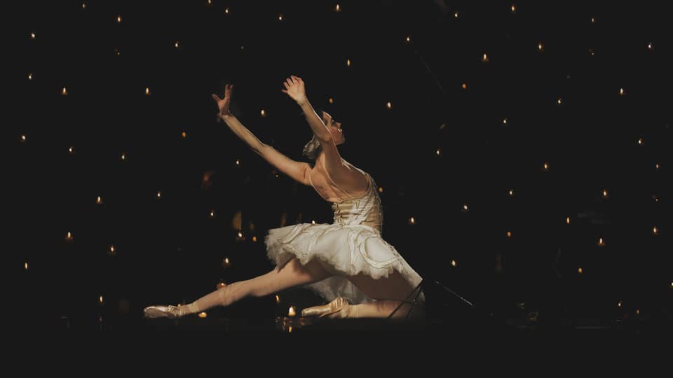 A ballerina dancing in front of a dark background