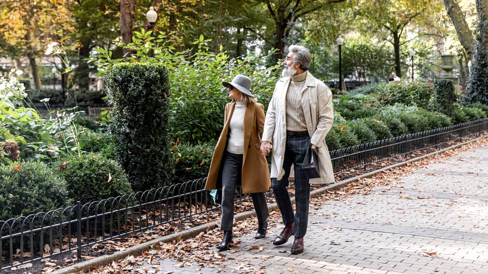 A man and woman walking next to a park.