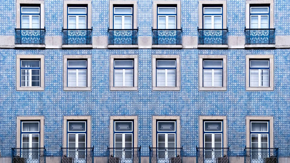 A blue tiled wall with many windows and balconies.