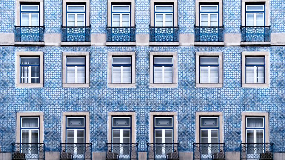 A blue tiled wall with many windows and balconies.