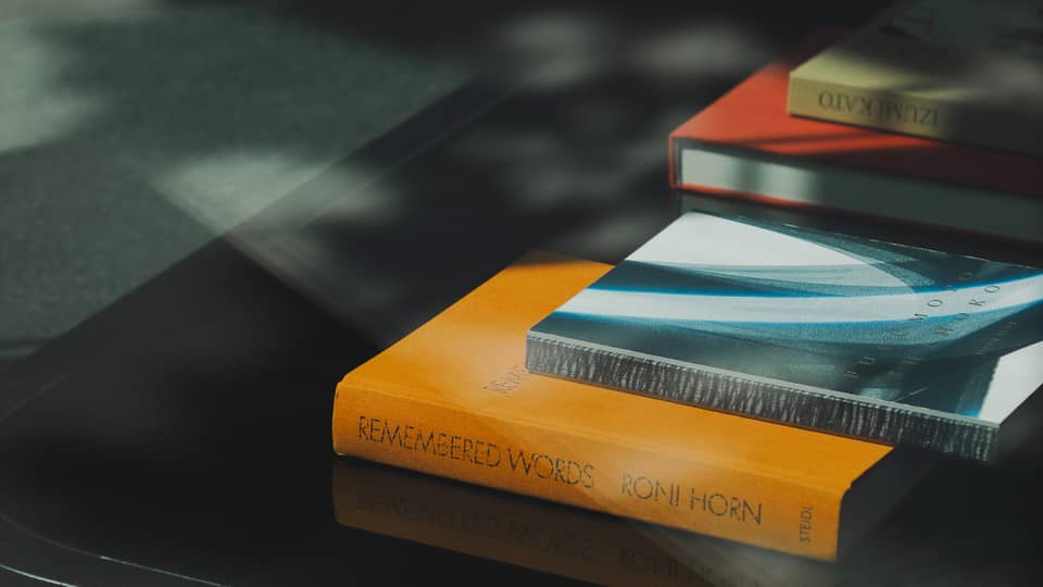 Orange, blue, red and green books stacked on a table