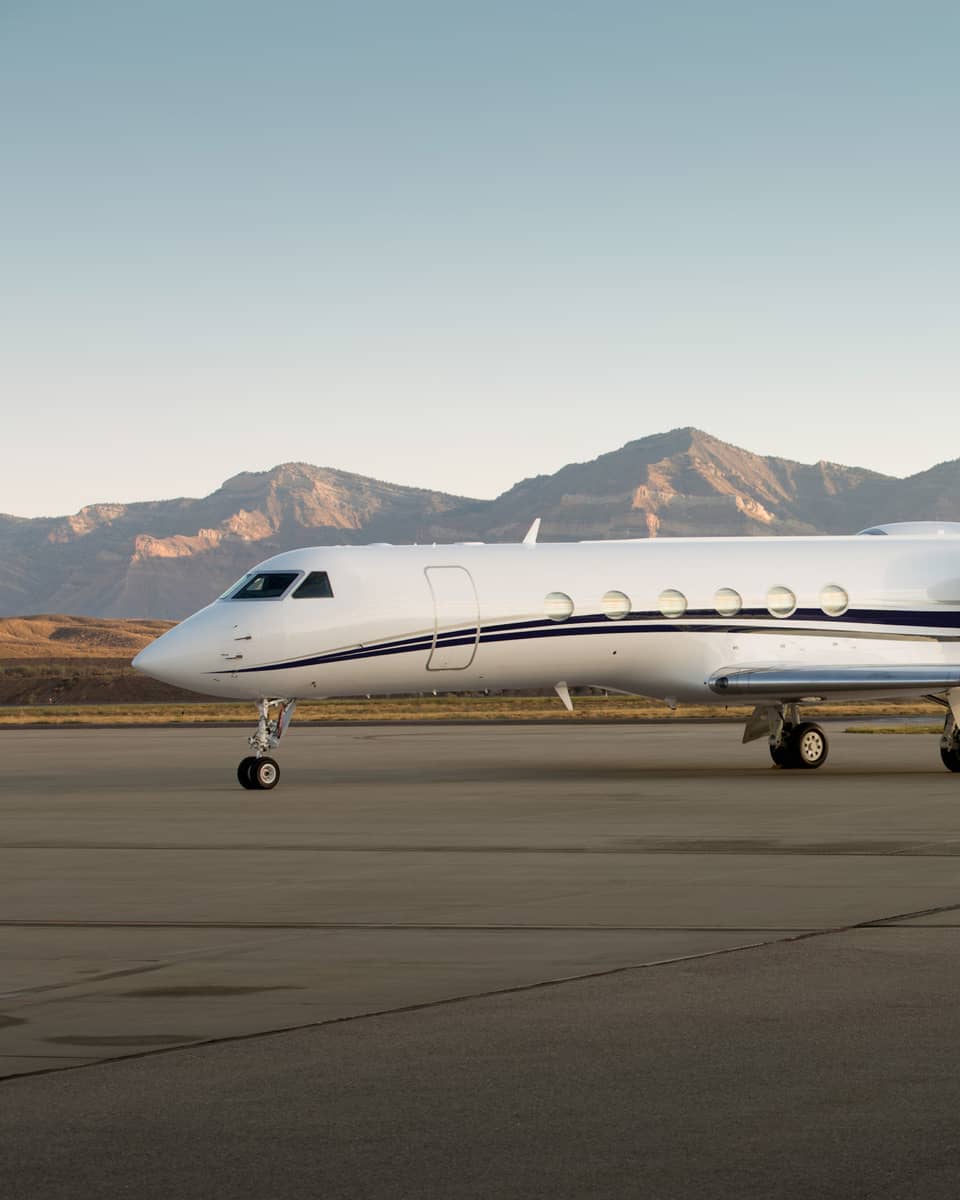 Private jet parked on a runway with mountain range in the background.