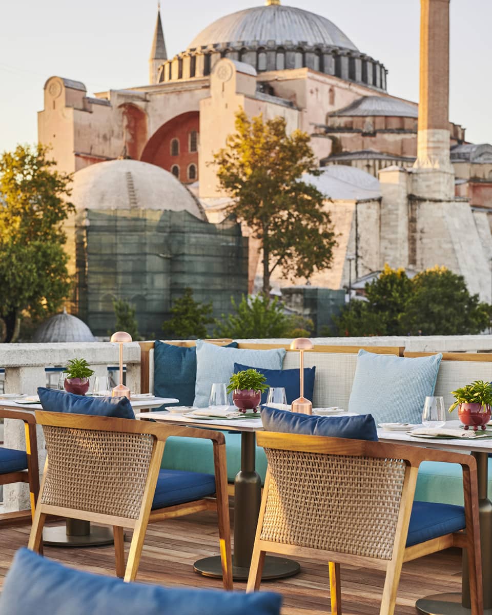 Terrace with outdoor table and blue cushioned chairs and the Blue Mosque in the background