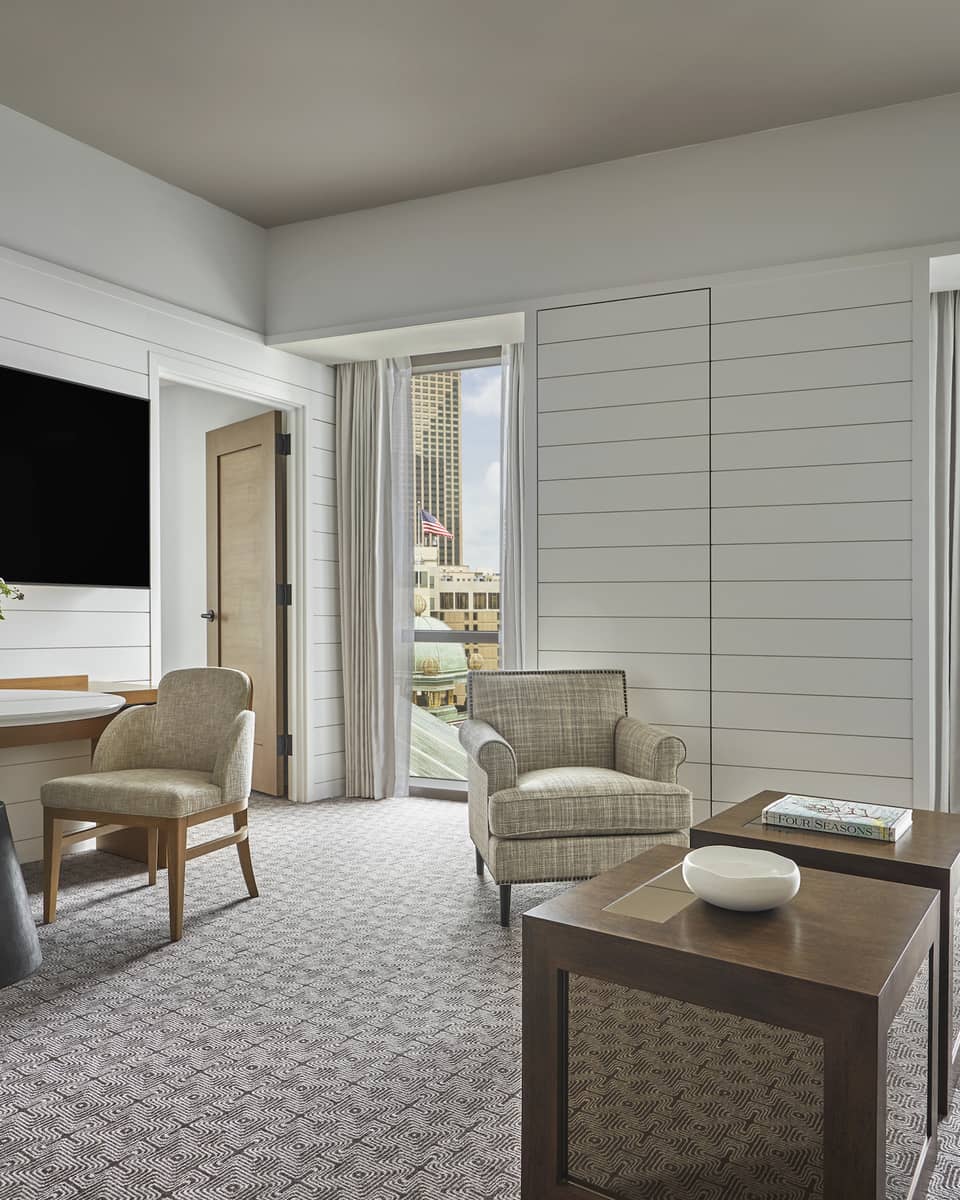 Suite with white panel walls, coffee table, sofa, two chairs, small table and television