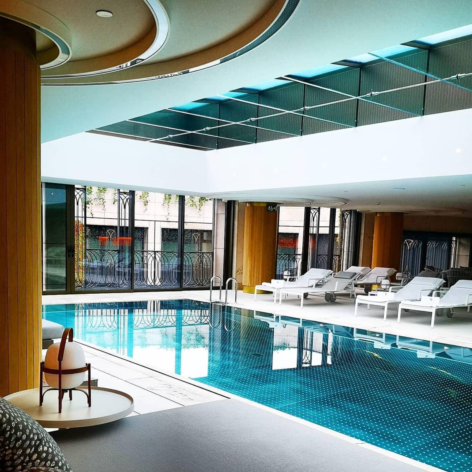A spacious indoor pool with large windows and a row of lounge chairs
