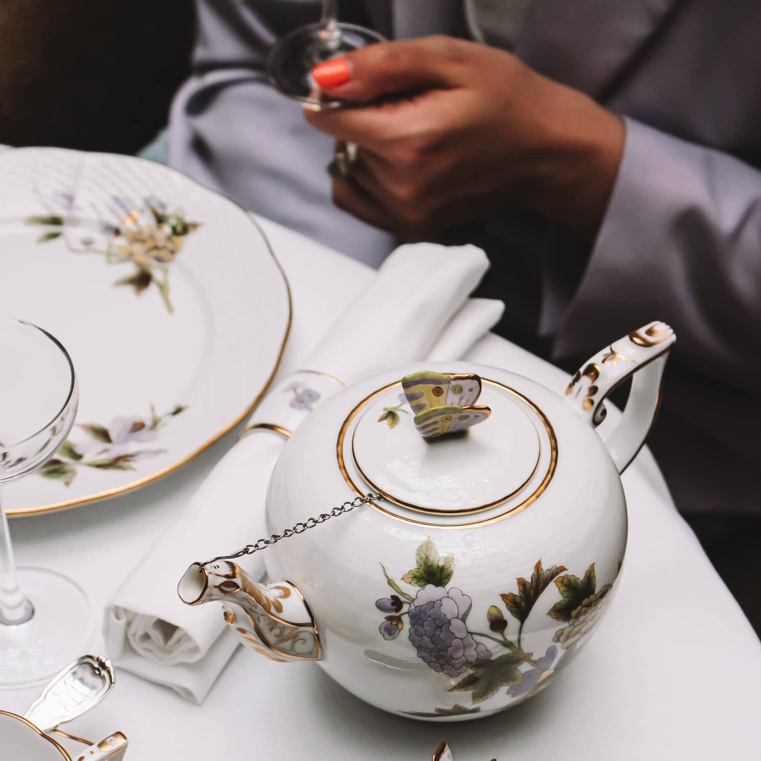 A white tea set with purple and yellow flowers on a white cloth table.