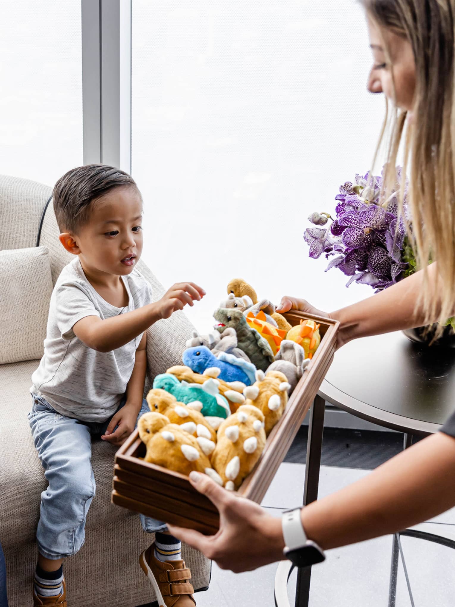 A child being offered a stuffed animal by a hotel team member.