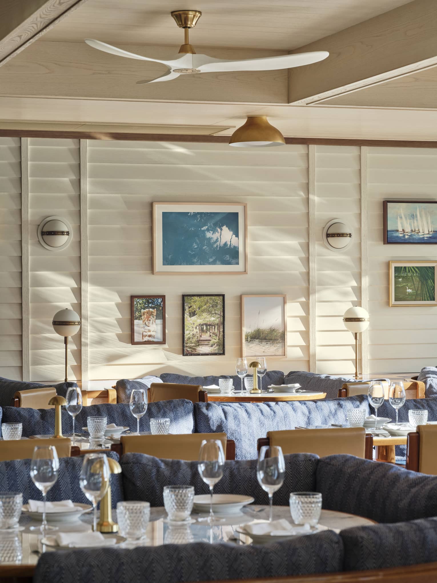 The interior of a restaurant with large booths with blue cushions and art on a wall.