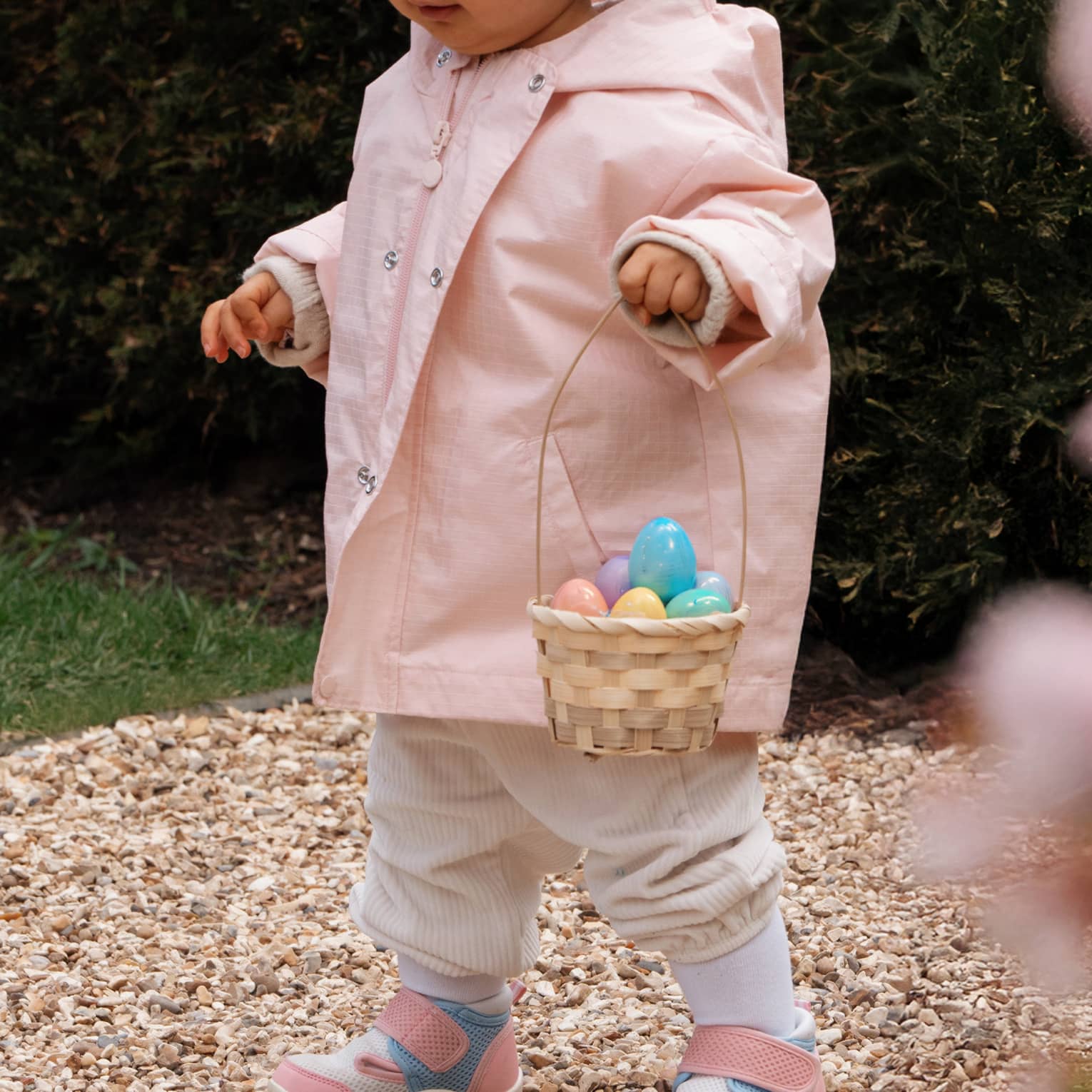 Child in pink coat with Easter basket and eggs