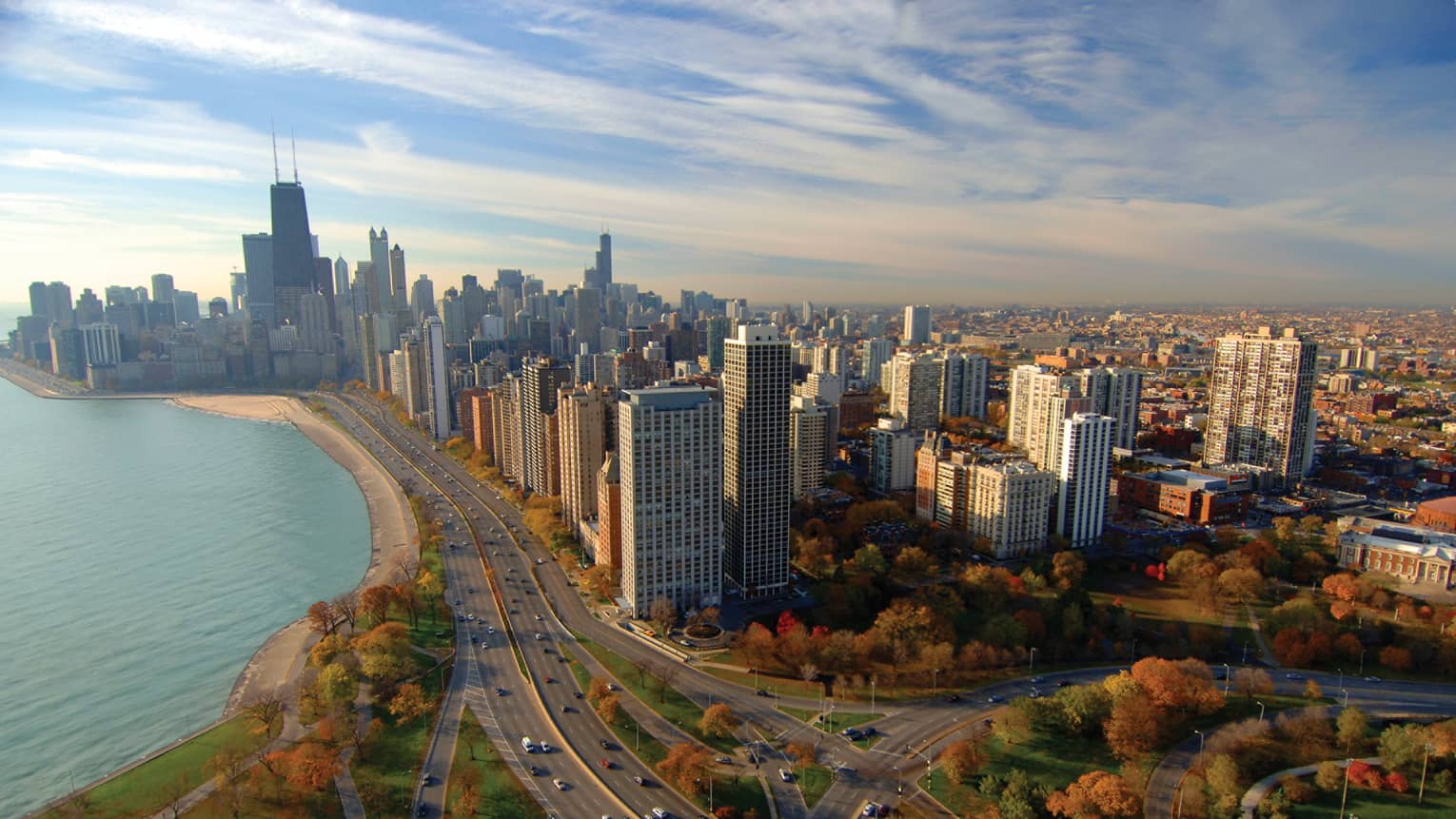 A road going through a city and trees with cars driving on it.