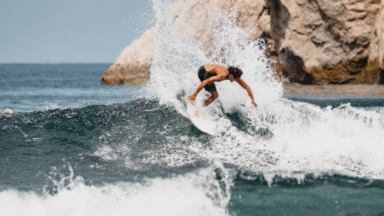 Surfer slashing down onto a wave