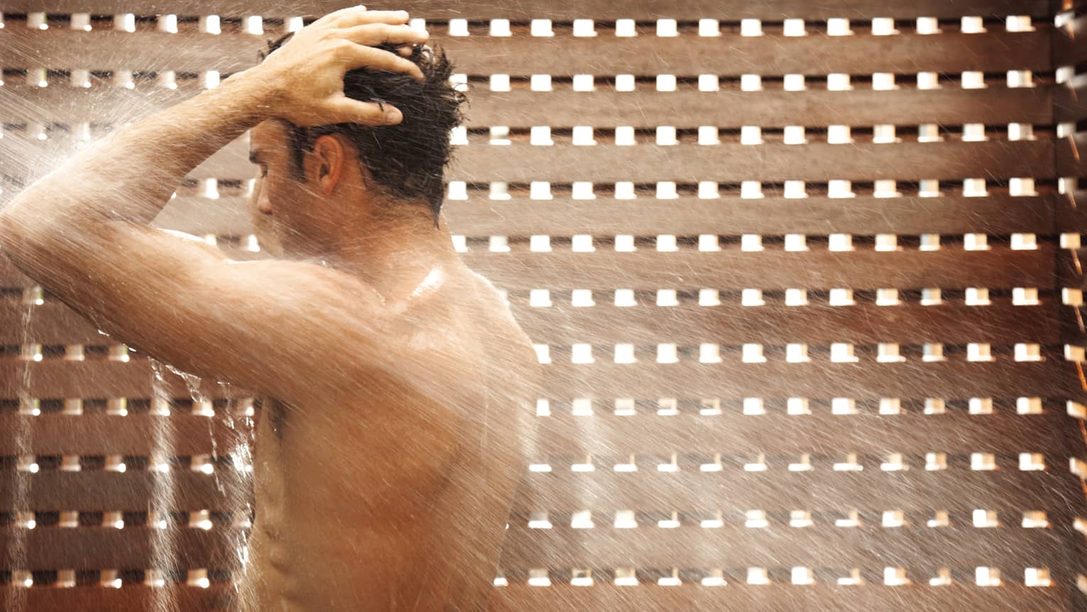 Man showering beside lattice wall in Spa