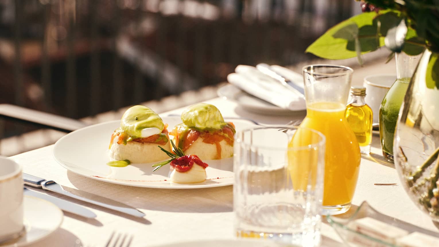 White plates topped with colourful brunch dishes on a table with glasses and a carafe filled with orange juice