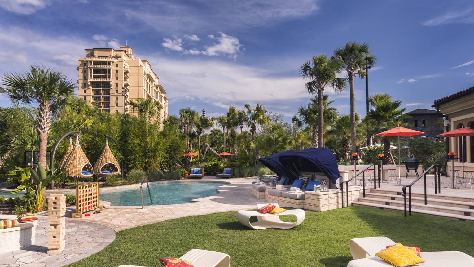 White patio chairs, hanging baskets, palm trees around swimming pool deck