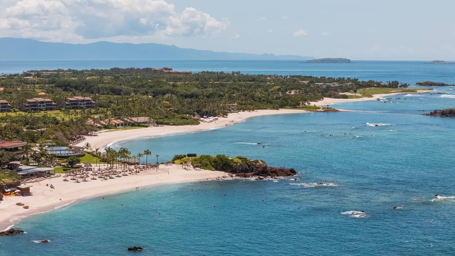 A bird's-eye view of a beachy coastline next to blue ocean waters