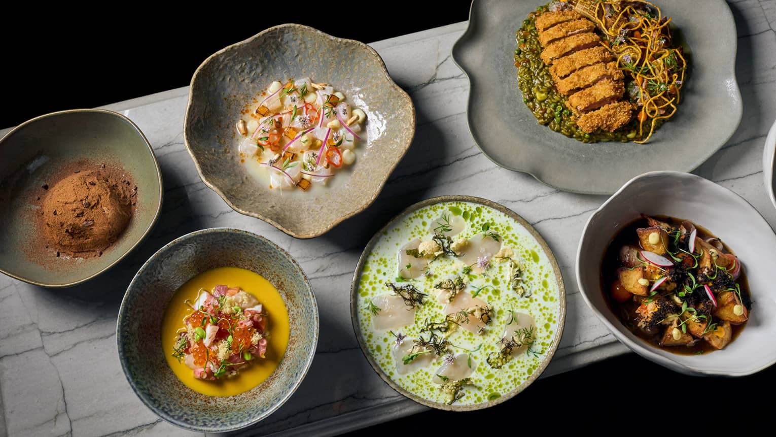 Pottery bowls of various culinary dishes set on a dining table