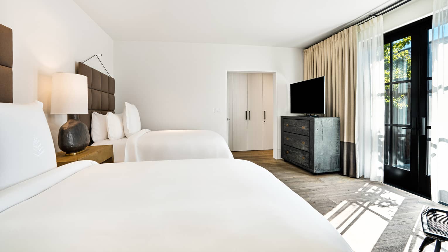 Luxury bedroom with two single beds and black French doors leading to outdoor terrace