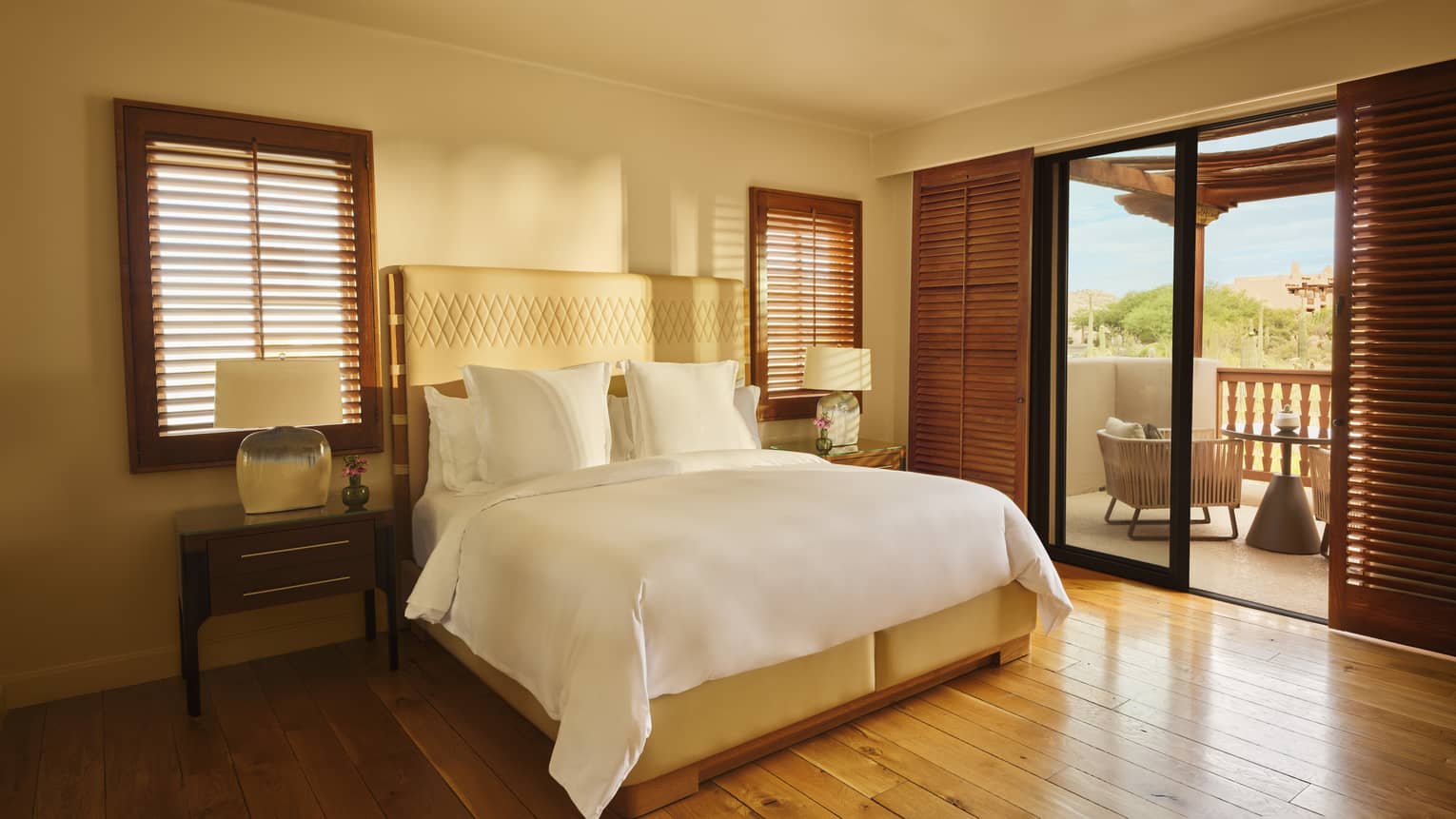 Bedroom with king bed, dark wooden shutter blinds, honey wooden floors and walk-out terrace