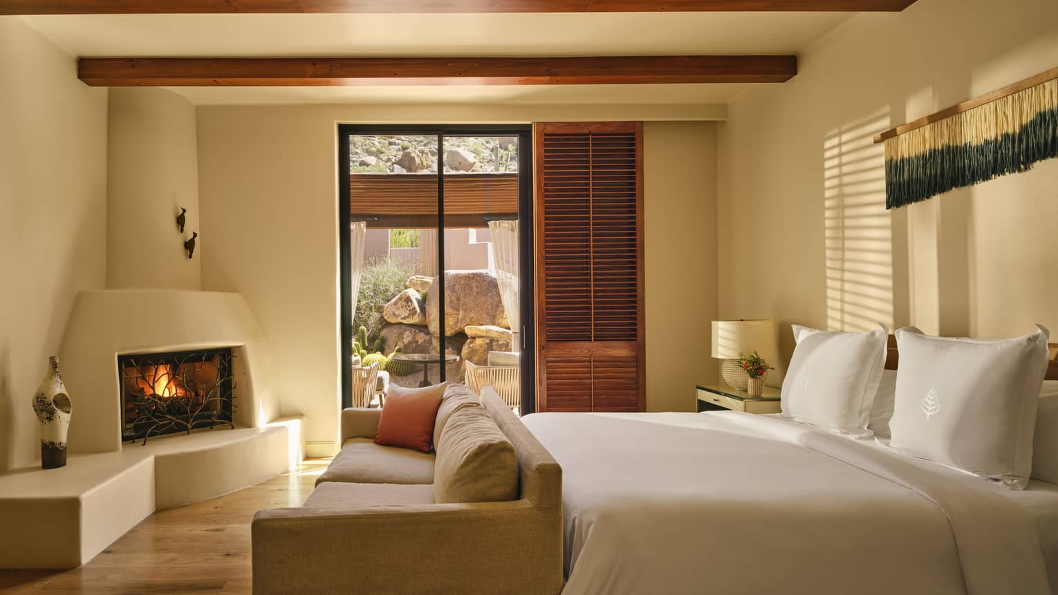 Luxury bedroom with king bed, sofa at the foot of the bed, kiva fireplace and walk-out terrace