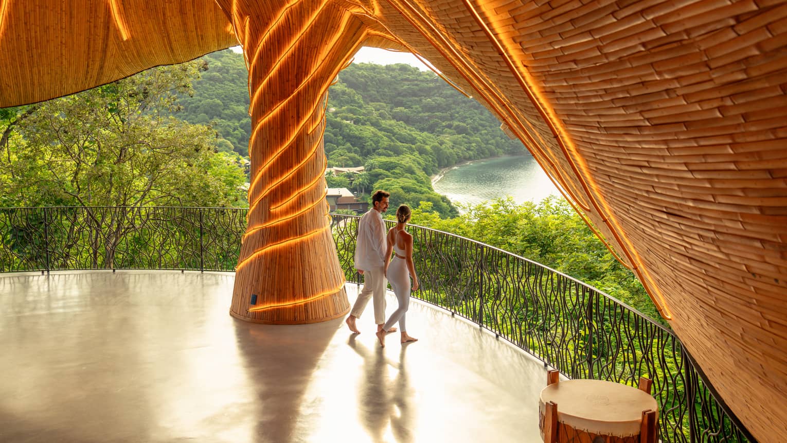 Two people walk beneath a wellness shala