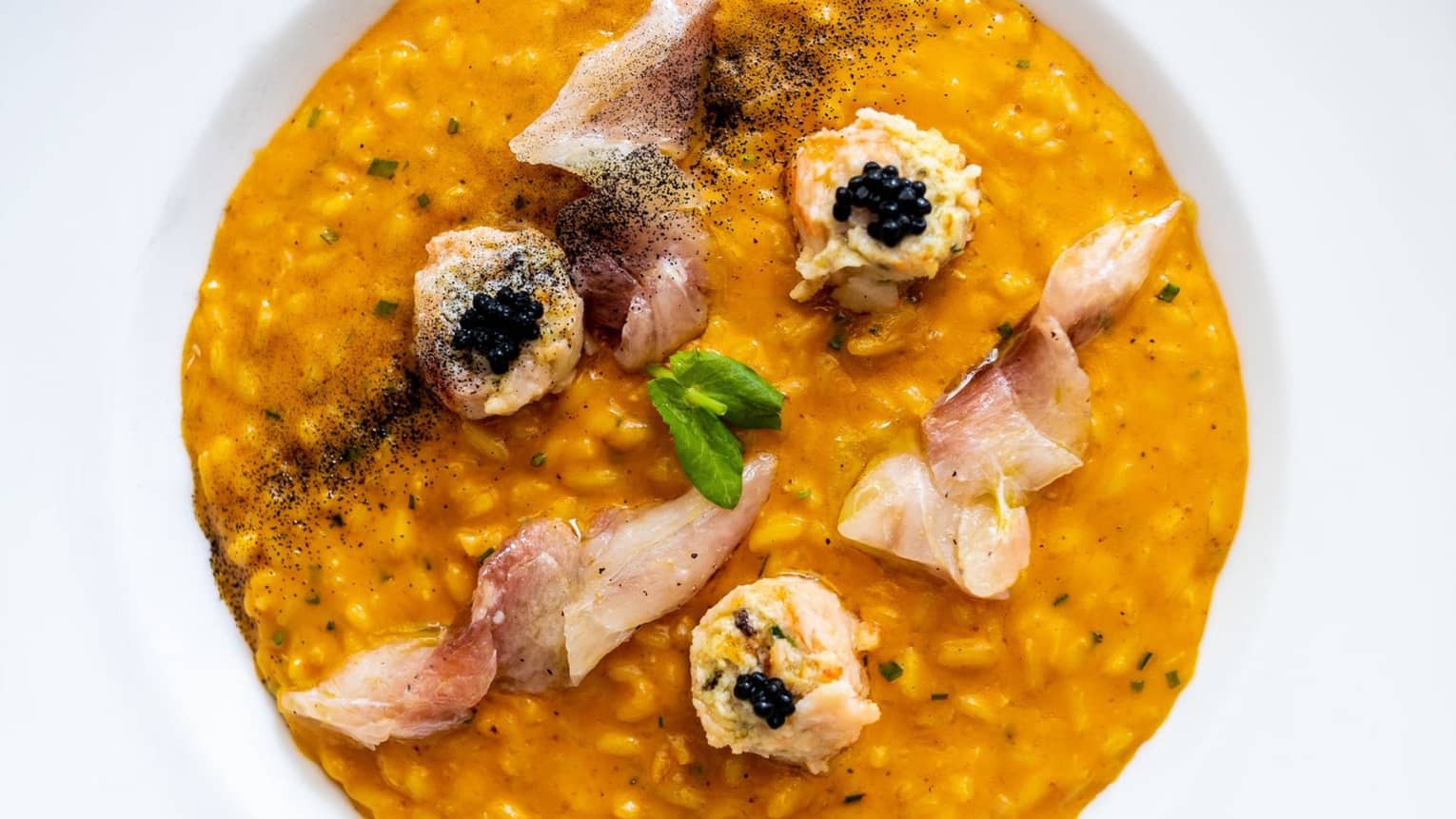 A vibrant, creamy risotto topped with seafood and caviar