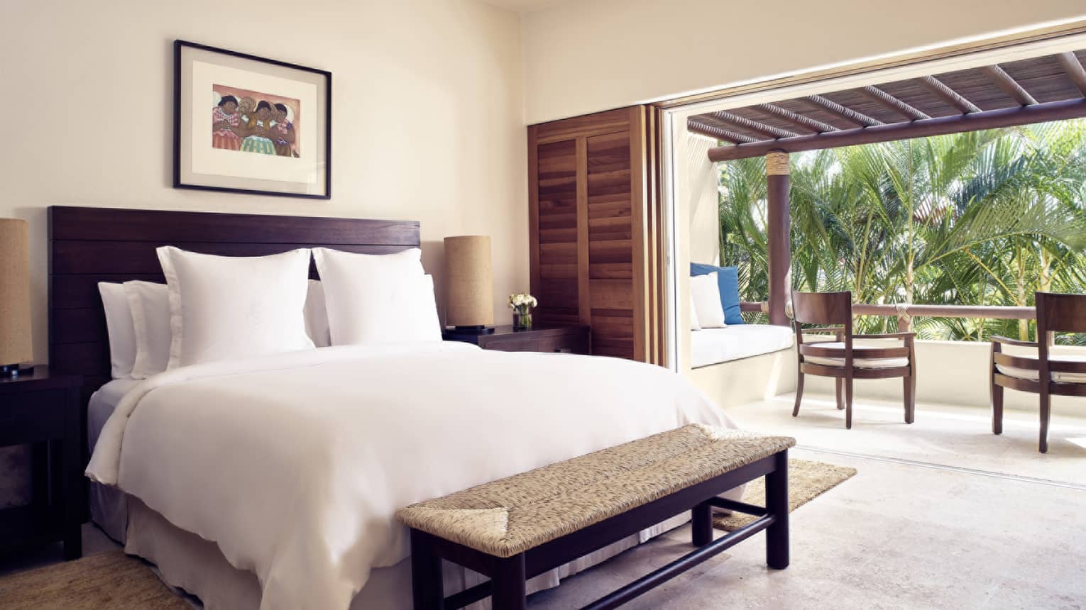 Bedroom with king bed, bench, walk-out balcony with palm tree view