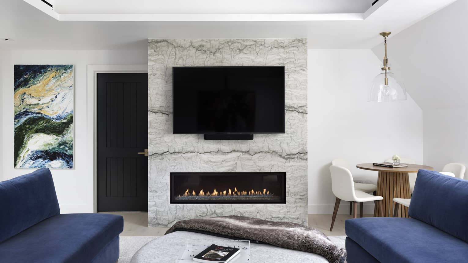 Modern fireplace with marble hearth, flat-screen TV, two dark blue sofas