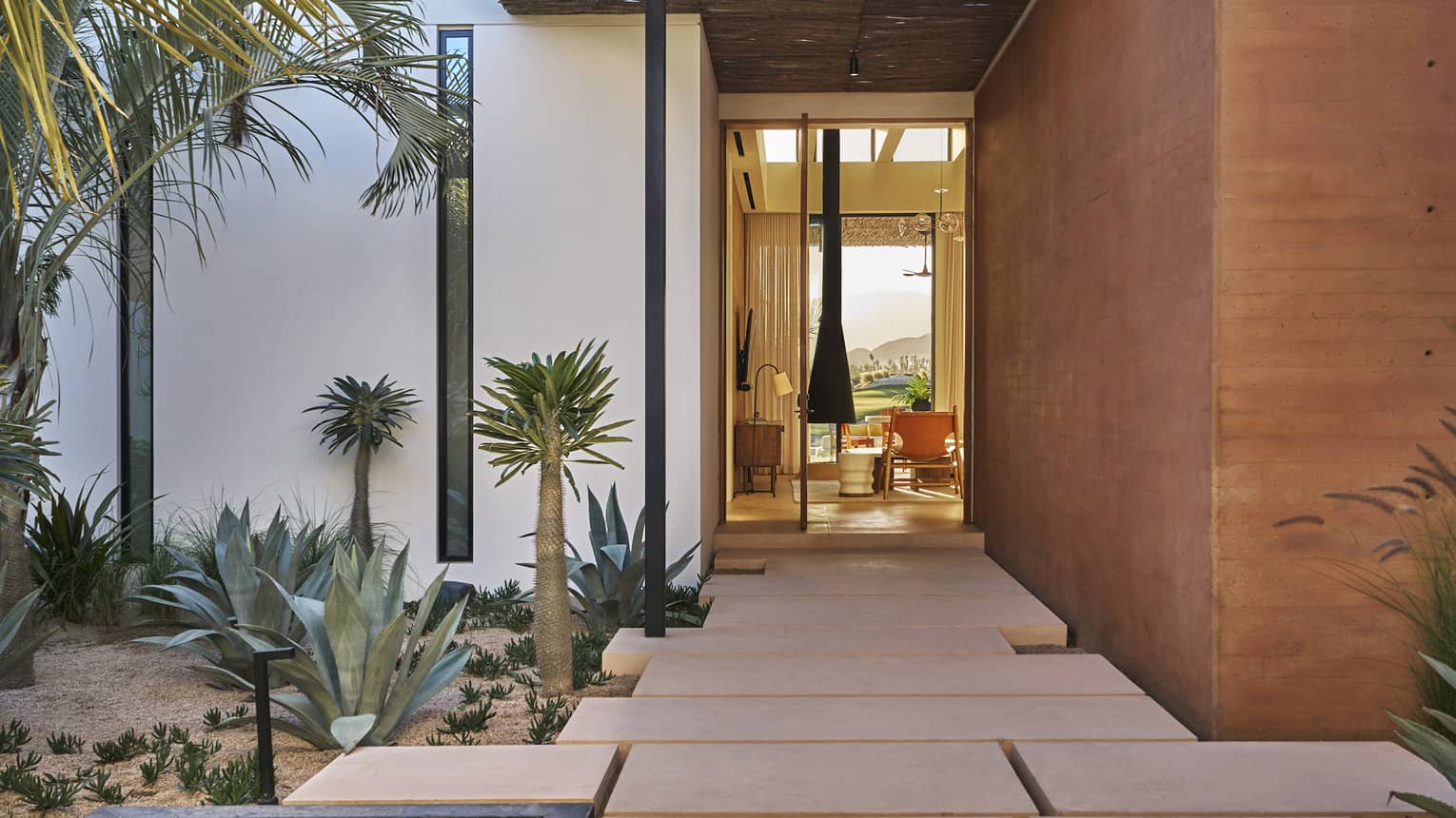 Modern entryway into a private villa, with water feature and large tiled walkway