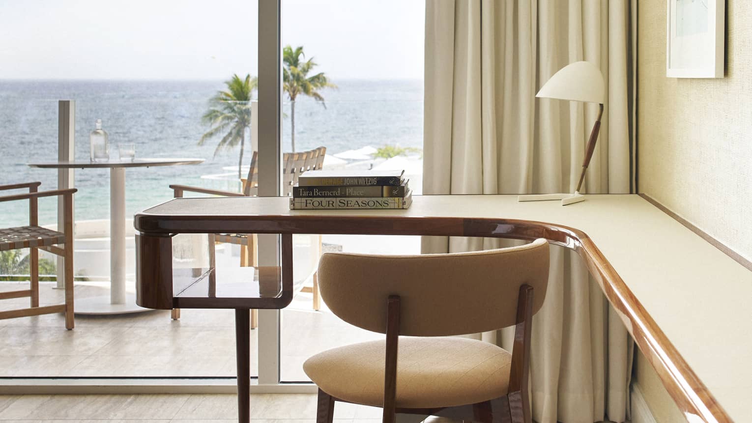 A workspace featuring a desk and chair, with a large window revealing a beautiful ocean view.