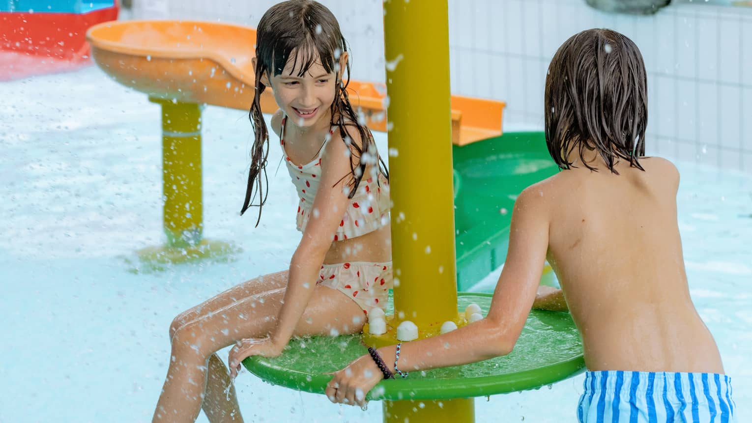 Two children playing on colourful feature of an indoor pool
