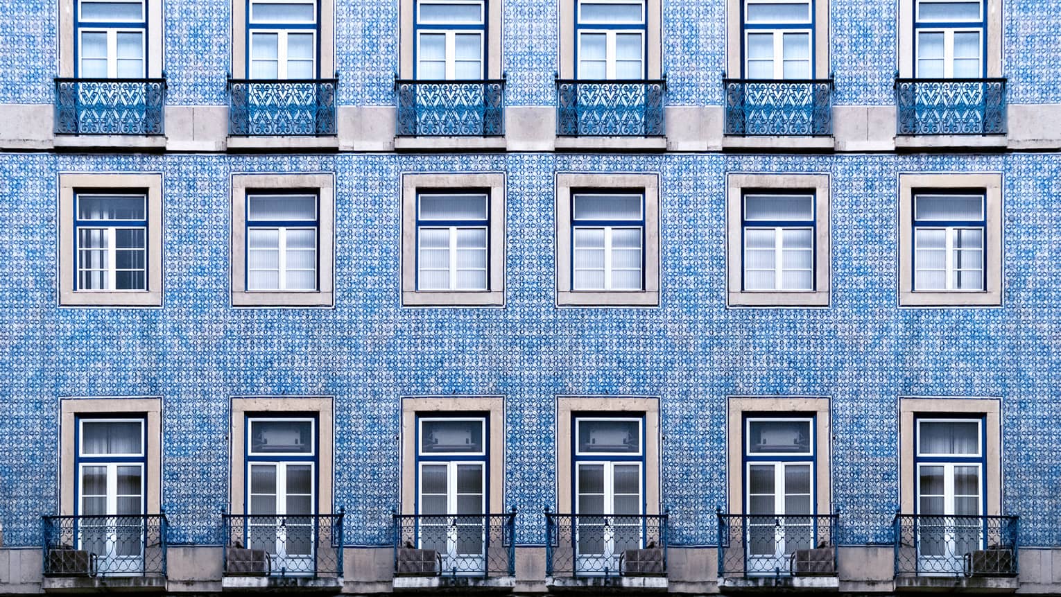 A blue tiled wall with many windows and balconies.