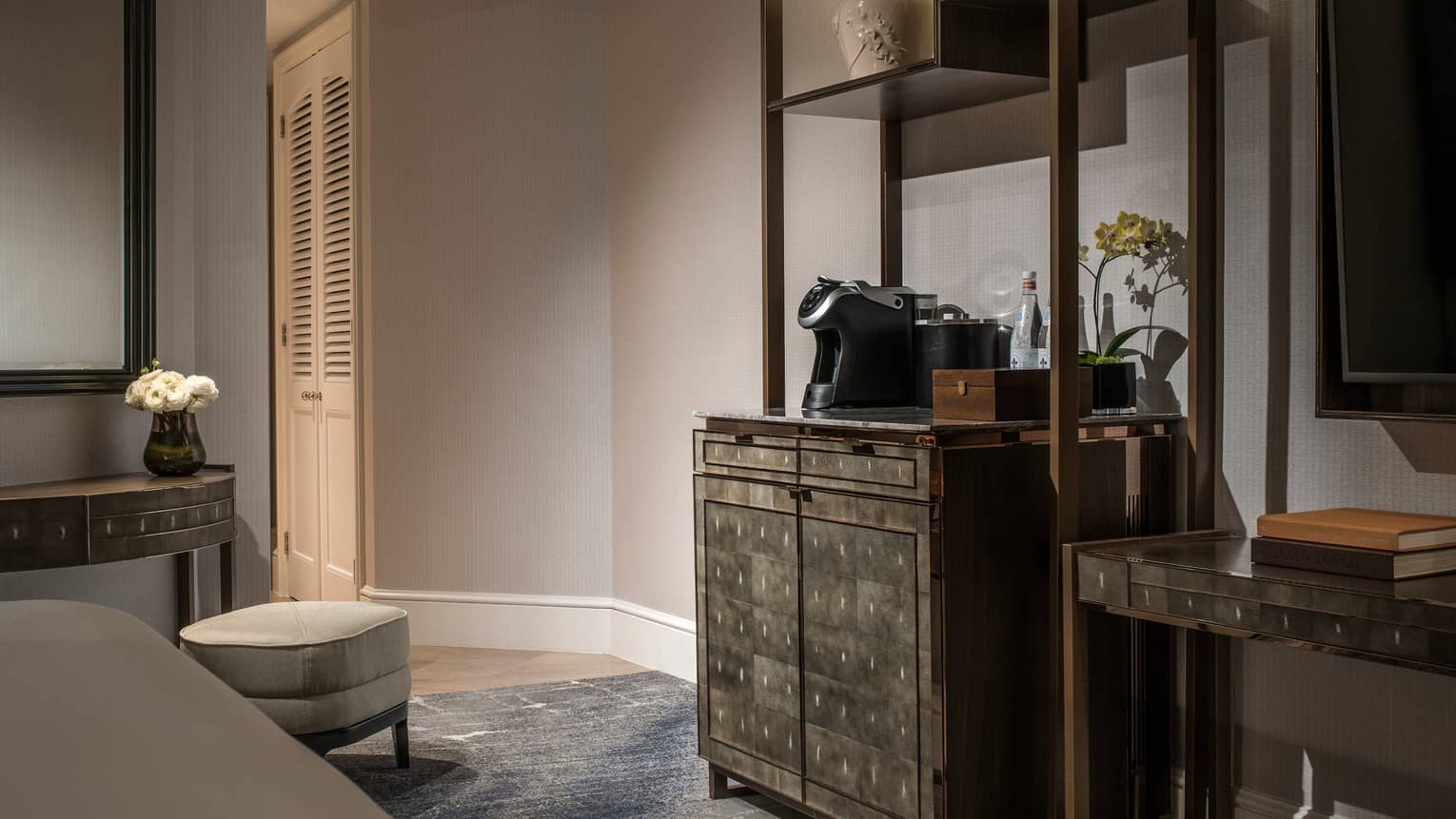 Elegant hotel room with a coffee station, marble-top cabinet and cosy seating area.