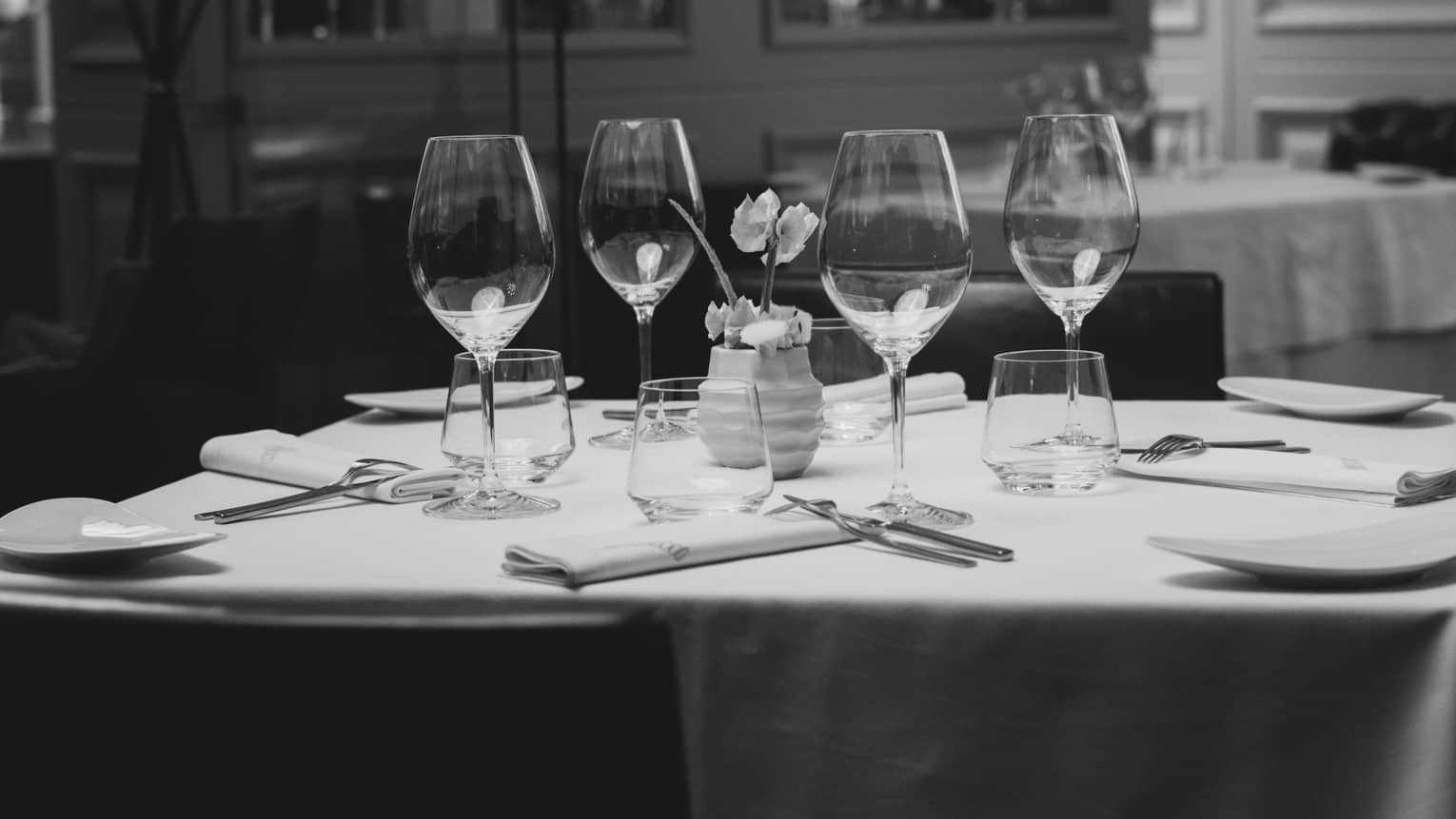 Dining table with place settings and a small flower centrepiece.
