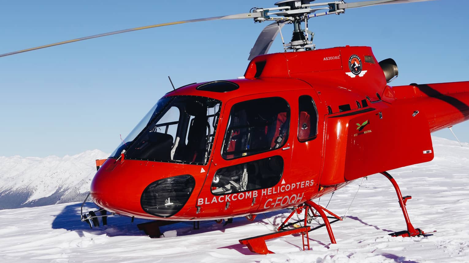 Red helicopter landing on white snow