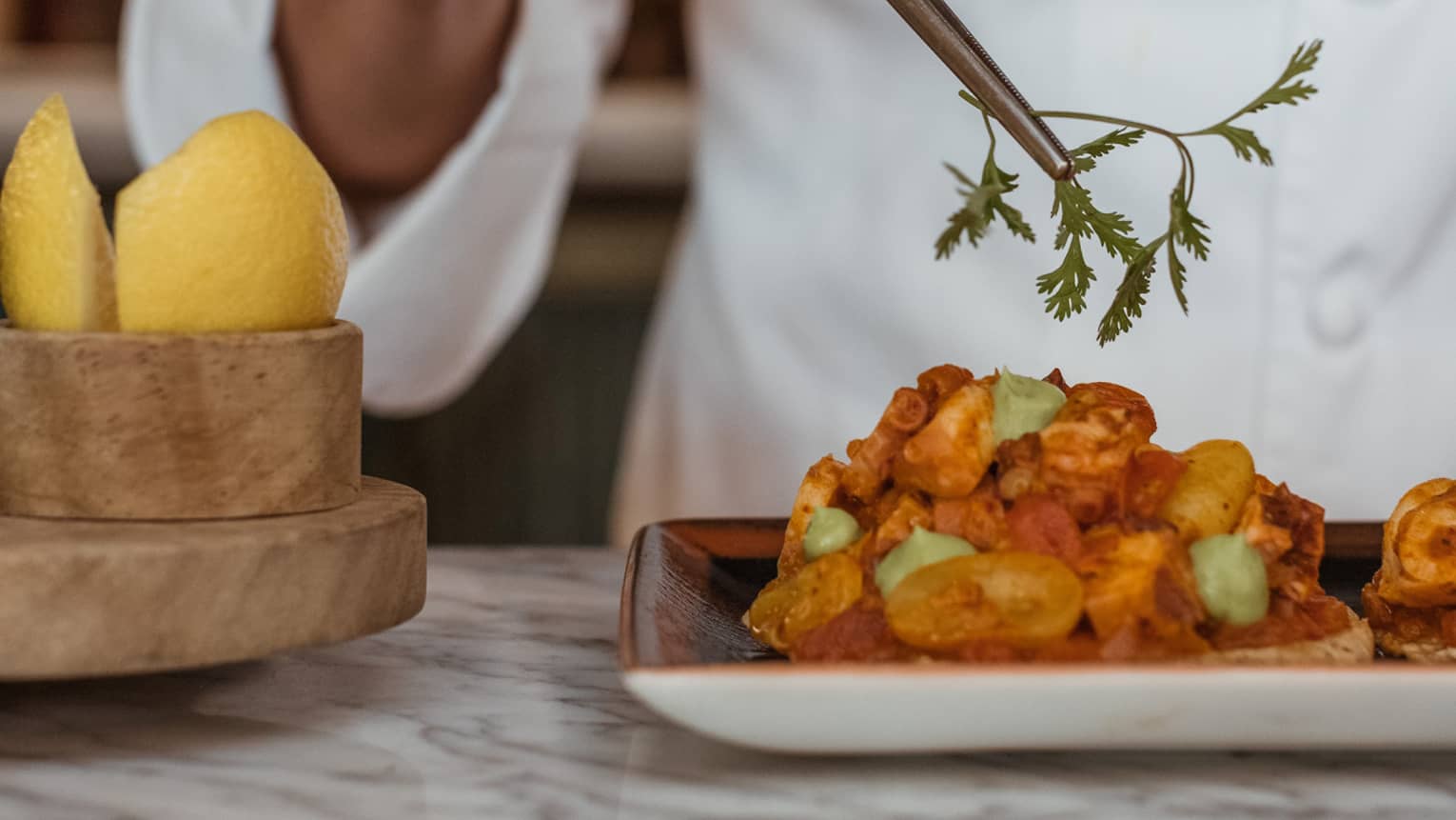 A chef picking up an herb with a utensil.