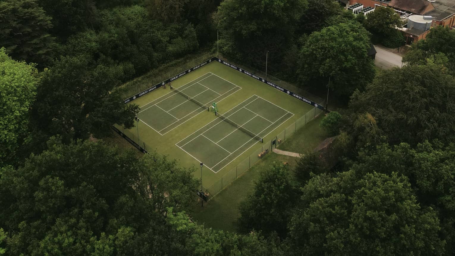 Aerial view of tennis courts nestled in a wooded area